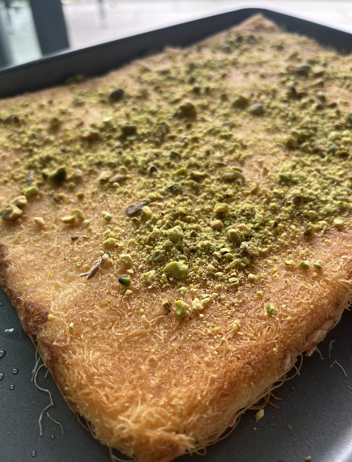 Close-up of golden-brown knafeh pastry with a sprinkle of pistachios